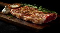 Juicy grilled ribeye steak with fresh rosemary sprigs and garlic on rustic wooden cutting board against dark background, food photography for restaurant menu.