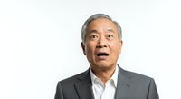Senior Asian male professional in gray blazer and white shirt expressing surprise or amazement against white background, suitable for business and corporate design projects.