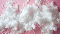 White fluffy clouds of cotton candy or smoke swirling against pink background creating dreamy abstract art composition with soft ethereal texture and movement.