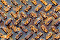 Grilled hot dogs with mustard and ketchup arranged in rows on dark background, overhead view showing charred texture and grill marks, food pattern for menu design.