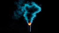 Glowing industrial chimney emitting bright cyan smoke against dark background, dramatic lighting effect creates mysterious atmospheric mood. Environmental concept.