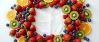 Fresh colorful fruit wreath with strawberries, blueberries, kiwi and orange slices arranged in circle on white background for healthy eating concepts.