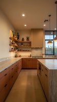 Modern kitchen interior with warm wood cabinets, marble countertops, floating shelves and pendant lighting in contemporary home design.