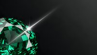 Sparkling emerald green gemstone with brilliant light rays on dark background for luxury jewelry and precious stone designs.