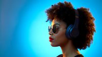 Young African American woman with curly afro hair wearing sunglasses and headphones in profile against vibrant blue background for music and lifestyle content.