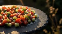 Fresh colorful vegetable salad with diced tomatoes, cucumbers and red onions on dark slate plate for healthy eating and Mediterranean cuisine.