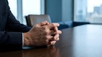 Professional businessman hands clasped on conference table in modern office boardroom with city skyline view for corporate meetings and negotiations.