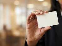 Close-up of a professional man's hand holding a blank white business card in an office setting, ideal for corporate branding and business communication concepts.