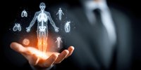 Digital hologram of human anatomy floating above businessman's hand with glowing organs and body systems visualization against dark background.