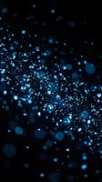 Blue glitter particles floating on black background with bokeh light effects creating magical sparkle dust for luxury design projects.