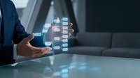 Businessman holding holographic digital cube with glowing interface elements in modern office environment for technology and innovation concepts.