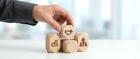 Business hand arranging wooden blocks with teamwork icons on office desk for corporate strategy and leadership development concepts.
