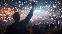 Silhouette of person with raised arm at concert against bright bokeh lights and crowd background, creating atmospheric celebratory mood at music festival.