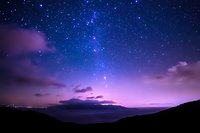 Stunning night sky with vibrant stars and Milky Way galaxy over mountain silhouettes. Purple and blue cosmic colors create magical atmosphere for astronomy content.