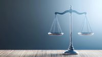 Metallic scales of justice on wooden surface against blue gradient background, symbolizing law, balance and judicial system in modern minimalist style.