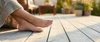 Woman's bare feet relaxing on wooden deck outdoors in warm sunlight creating peaceful summer wellness moment for spa and relaxation concepts.