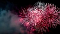 Vibrant pink and red fireworks exploding against dark night sky, creating festive atmosphere for celebrations, holidays, and special events.