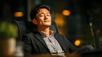 Relaxed Asian businessman sitting in office chair with eyes closed and peaceful expression during break time in modern workplace.