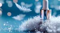 Delicate white feather floating above silver dropper bottle on crystalline frost surface against dreamy blue bokeh background. Cosmetic skincare winter concept.