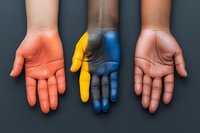 Three open palms painted in red, yellow and blue colors shown against dark background, representing diversity, unity and creative expression.