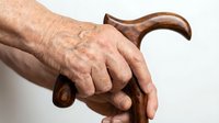 Elderly hands gripping wooden walking cane showing aging, mobility support, senior care, healthcare assistance, independence, daily living aid.