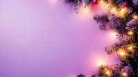Glowing Christmas lights and pine branches create festive border frame on purple background with copy space for seasonal holiday greeting cards.
