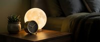 Cozy bedroom nightstand with glowing moon lamp, alarm clock and succulent plant creating warm ambient lighting for relaxation and sleep.