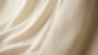 Luxurious cream silk fabric with elegant flowing folds and soft draping texture for fashion design and textile backgrounds.