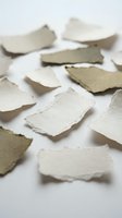 Torn handmade paper pieces scattered on white surface with natural textures and organic edges for craft projects and artistic compositions.