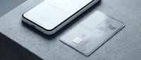 Transparent credit card and smartphone on gray concrete surface, modern minimalist fintech concept for digital banking and contactless payment.