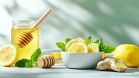 Fresh honey with lemon slices, mint leaves and ginger root on white table. Natural ingredients for healthy tea, immune support and wellness remedies.