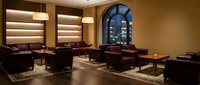 Elegant upscale restaurant interior with burgundy leather seating, warm lighting and arched windows creating sophisticated dining atmosphere for hospitality design.