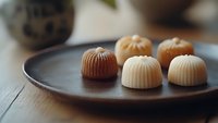 Assorted gourmet chocolate bonbons with ribbed shells arranged on dark ceramic plate, luxury confectionery treats for gifting and indulgence occasions.