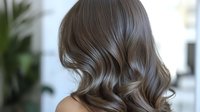Luxurious wavy brown hair styled with soft curls cascading down woman's back, showcasing professional salon hairstyling technique and healthy shine. Perfect for beauty advertising.