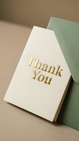Elegant thank you card with gold foil lettering leaning against a sage green envelope on a warm beige background, perfect for weddings and events.
