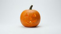 Carved orange pumpkin jack-o-lantern with glowing candle light isolated on white background for Halloween decoration and autumn seasonal design projects.