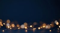 Warm golden string lights with soft bokeh effect against dark blue background, suitable for holiday, festive, and seasonal marketing materials.