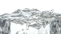 Clear water splashing over ice cubes on white background, isolated and ready for beverage, refreshment, and cooling design projects.