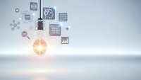 Glowing light bulb with brain filament surrounded by business icons representing innovation, creativity and strategic thinking in modern workspace.