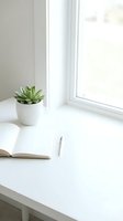 Minimalist white desk workspace with succulent plant, open notebook and pen by bright window for productivity and home office design.