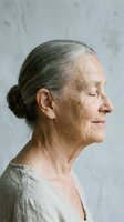 Senior woman with gray hair in profile, wearing casual beige shirt against neutral background. Mature female portrait for healthcare, wellness, aging, and lifestyle editorial use.