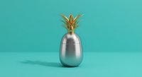 Metallic silver pineapple with golden crown on turquoise background. Modern minimalist tropical fruit decoration for contemporary interior design and lifestyle concepts.