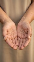 Elderly hands cupped open in giving gesture showing wrinkled palms and fingers of senior person offering help or receiving support in warm natural light.