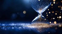 Glowing hourglass with falling golden sand against dark background, magical sparkles and bokeh lights creating mystical atmosphere and reflection.
