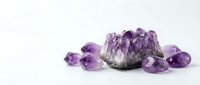 Purple amethyst crystal cluster with tumbled gemstones on white background. Natural healing stones for meditation, spiritual wellness and jewelry making.