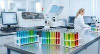 Female scientist working in modern laboratory with colorful test tubes and advanced equipment for research and analysis.