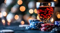 Glass of red wine with poker chips on dark table against blurred bokeh lights background, creating atmospheric casino gambling ambiance.