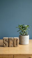 Wooden SEO blocks with succulent plant in concrete pot on desk against blue wall for digital marketing and search engine optimization concepts.