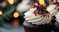 Chocolate cupcake with vanilla buttercream frosting topped with red berries and star anise against blurred holiday lights background, festive winter dessert.