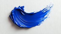 Vibrant blue paint stroke with textured brush marks and dynamic curved shape on white background, showing artistic movement and depth. Isolated makeup cosmetic swatch.